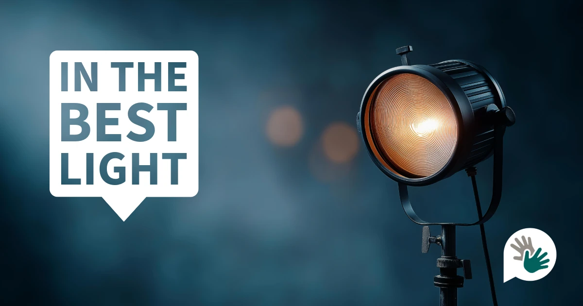 Studio spotlight shining brightly against a dark blue background with the words “In the Best Light” displayed in a speech-bubble graphic, symbolising visibility, clarity and presenting stories or people positively and professionally.